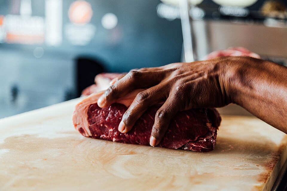 Peça de carne sendo preparada na bancada do açougue